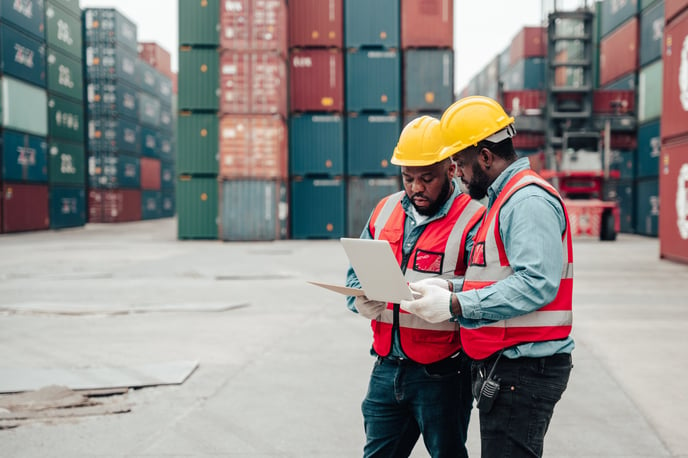 Two people in hard hats consult a clip board in a stock yard.